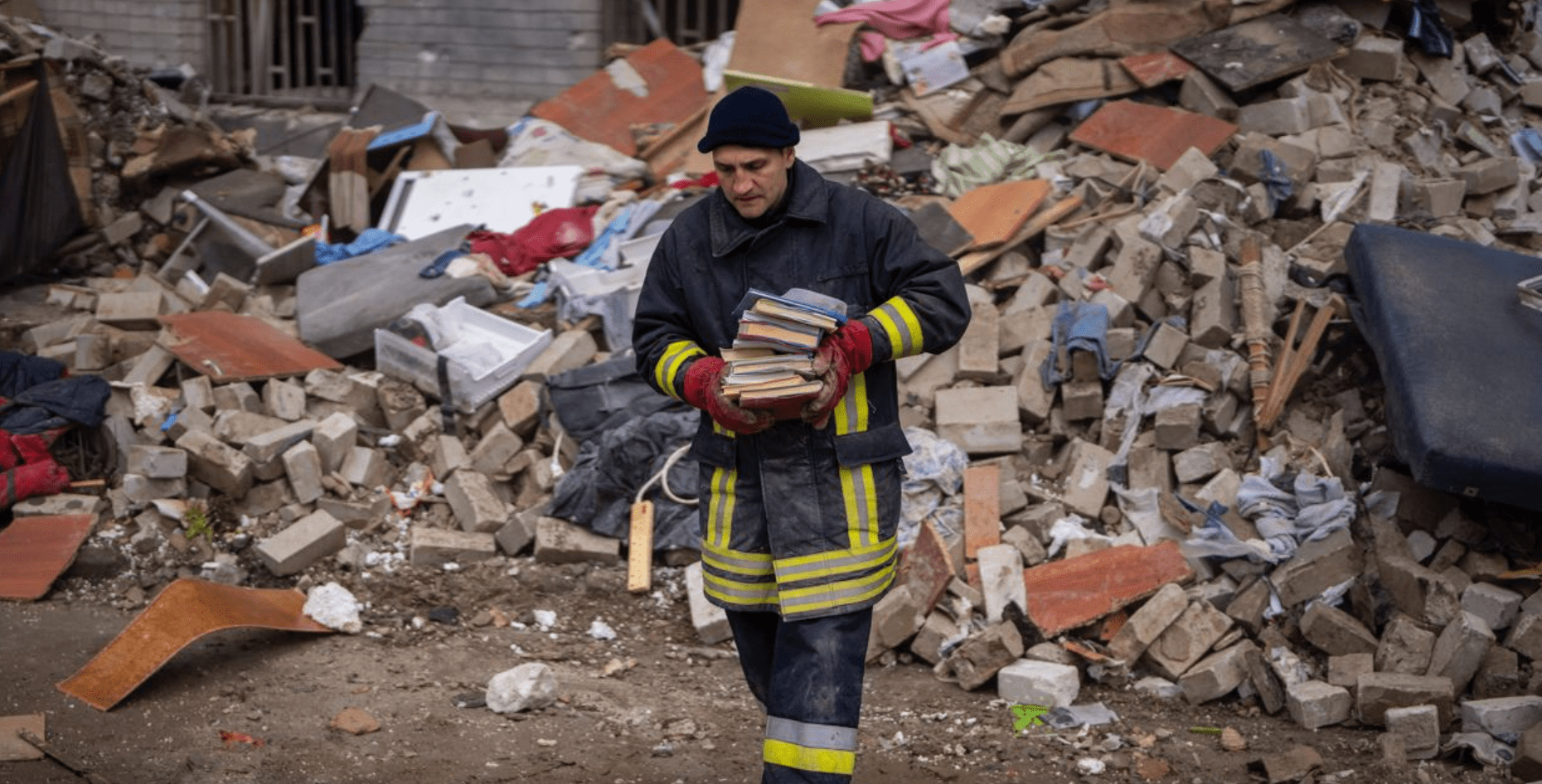 fire fighter removing books from wreckage